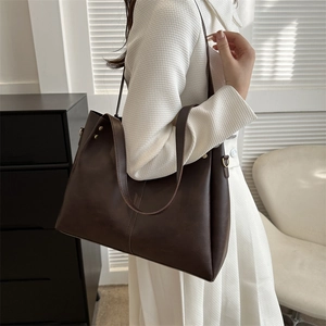 Detail view of a large dark brown matte PU leather tote bag with side metal rivet accents