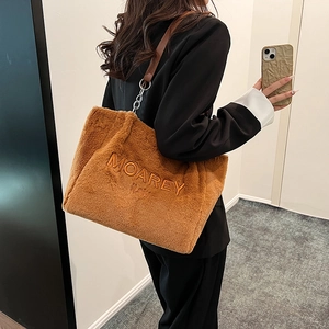 Plush brown tote bag with MOAREY embroidery and dark leather strap on a shoulder