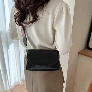 Detail of minimalist black PU crossbody bag with unique geometric woven shoulder strap