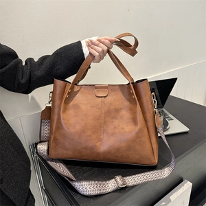 Detail of vintage brown PU tote bag with wide geometric woven strap and gold hardware