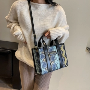 Detail of trendy faux snakeskin tote bag with adjustable strap and Tote Bag lettering