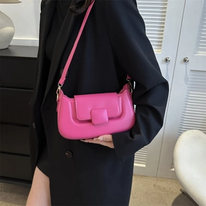 Detail of bright pink PU leather shoulder bag with gold hardware on a black suit