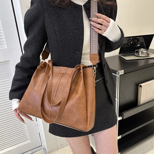 Detailed view of brown retro PU leather tote bag with stylish colorful woven shoulder strap