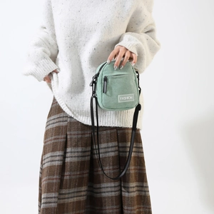 Detail of mint green corduroy crossbody bag with FASHION label and thin strap
