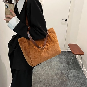 Detail view of winter plush tote bag in caramel brown with embroidered lettering and leather strap