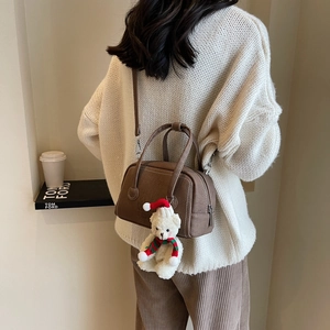 Brown vintage faux leather crossbody bag with a cute teddy bear charm on a warm outfit