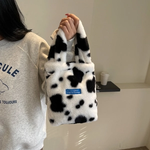 Detailed view of plush cow print handbag with soft faux fur texture and blue brand label