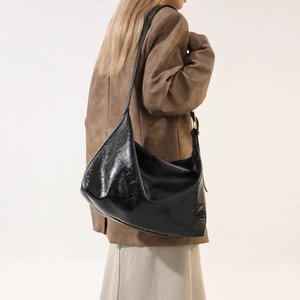 Detail of the black glossy Hobo bag showing smooth leather texture and side metal buckle
