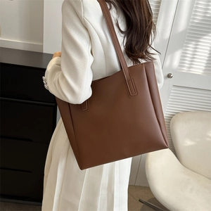 Brown faux leather tote bag showing shoulder strap drop and smooth matte texture on model