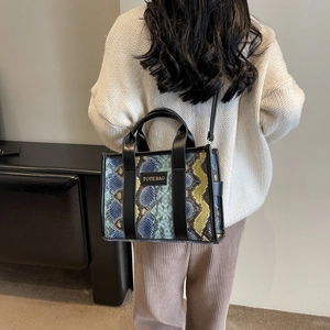 Model wearing snake pattern PU leather tote bag with shoulder strap in stylish interior