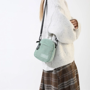 Detail of mint green corduroy handbag featuring front pocket and FASHION label patch