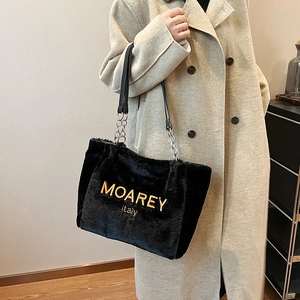 Detailed shot of black plush tote bag with gold lettering and silver chain strap