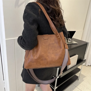 Detail view of brown tote bag with vintage texture and stylish geometric woven strap