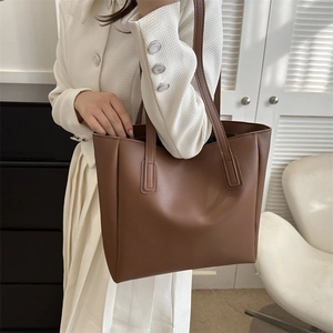 Close-up of a minimalist brown PU leather tote bag with fine texture and reinforced straps