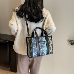 Close-up of a multi-color snakeskin texture tote bag worn as a crossbody shoulder bag