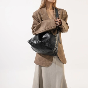 Detail of black glossy Hobo bag showing soft pleated texture and wide shoulder strap