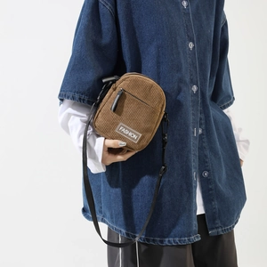 Detailed texture of brown corduroy crossbody bag with fashion label and zipper pocket