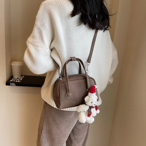 Brown grainy leather handbag with MUO SHAP embossing and a cute bear pendant charm