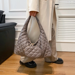 Detail of grey quilted crossbody bag with a round coin purse and gold hardware