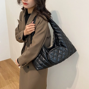 Detail of black quilted hobo bag with side coin purse on model's shoulder in soft light