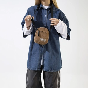 Detail of brown corduroy crossbody bag texture with FASHION label and zipper pocket