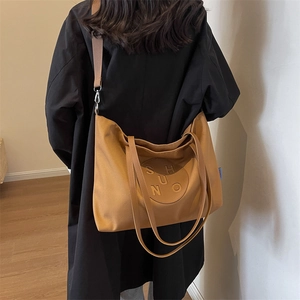 Detailed view of Mustard canvas crossbody tote with wide strap on black coat