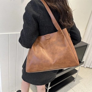 Detailed view of brown PU leather tote bag with magnetic flap and embossed logo