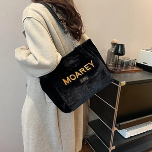 Close-up of black plush tote bag with gold embroidery and stylish silver chain detail
