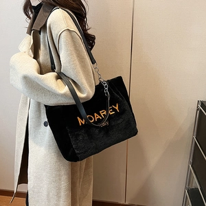 Detail of plush black tote bag featuring orange MOAREY embroidery and metal chain strap