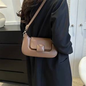 Detail view of brown PU shoulder bag featuring square buckle and gold hardware on model
