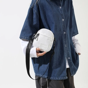 Close-up of white corduroy small square bag with fashion label on denim shirt