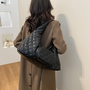 Detail of black quilted faux leather crossbody bag with matching round coin purse on shoulder