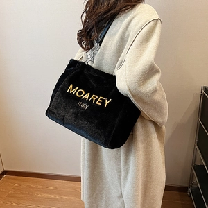 Detail of plush black tote bag featuring gold embroidery and metal chain leather strap