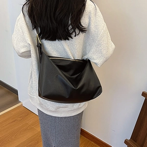 Rear view of a minimalist black lychee grain leather hobo bag with gold hardware detail