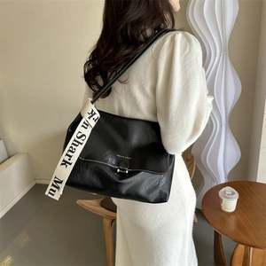 Detail of black soft PU leather tote bag with jacquard strap and golden metal buckle