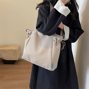 Detail of minimalist beige canvas tote bag with drawstring closure and blue woven brand label