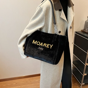 Detail of black faux fur tote bag with gold embroidery and metal chain strap
