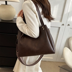 Deep brown faux leather tote bag with wide jacquard strap worn by female model
