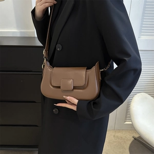 Detailed close-up of a brown PU leather crossbody bag with a square buckle on black blazer