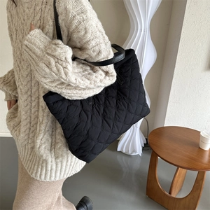 Gros plan sur un sac cabas noir en nylon matelassé avec des poignées en cuir brillant
