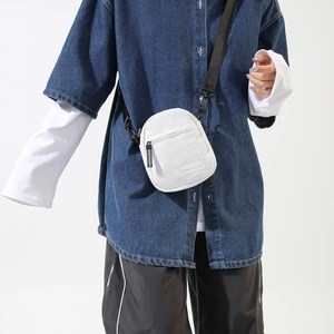Detail of white corduroy crossbody bag featuring a fashion label and black strap