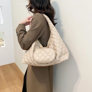 Detailed side view of beige quilted crescent shoulder bag with small hanging pouch
