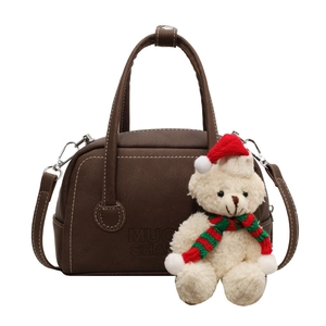 Brown leather doctor bag with white stitching and festive bear charm in studio lighting