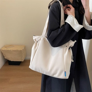 Detail view of large cream canvas tote bag with adjustable drawstring side closure