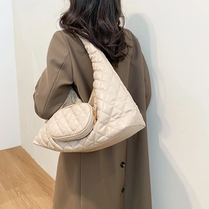 Detail of beige quilted crescent shoulder bag with mini round coin purse pendant