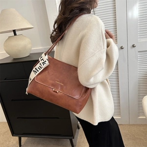 Detailed view of brown PU leather shoulder bag featuring a stylish contrast lettered ribbon