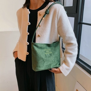 Detail of green suede shoulder bag with onwards and upwards embroidery and knotted strap