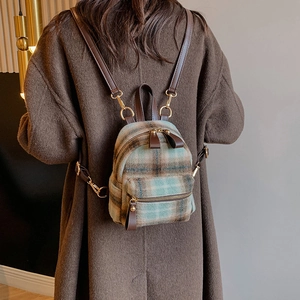 Mini zaino in lana a scacchi verdi e marroni con spalline in pelle su una modella