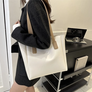Detail of high-quality PU leather cream tote bag with brown straps in office setting