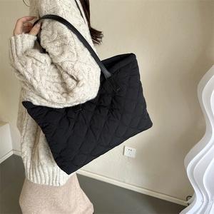 Sac fourre-tout noir matelassé avec de longues lanières en cuir porté par un mannequin